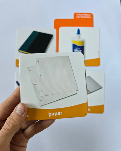 Sanastokortti kädessä, taustalla näkyy lisää sanastokortteja.